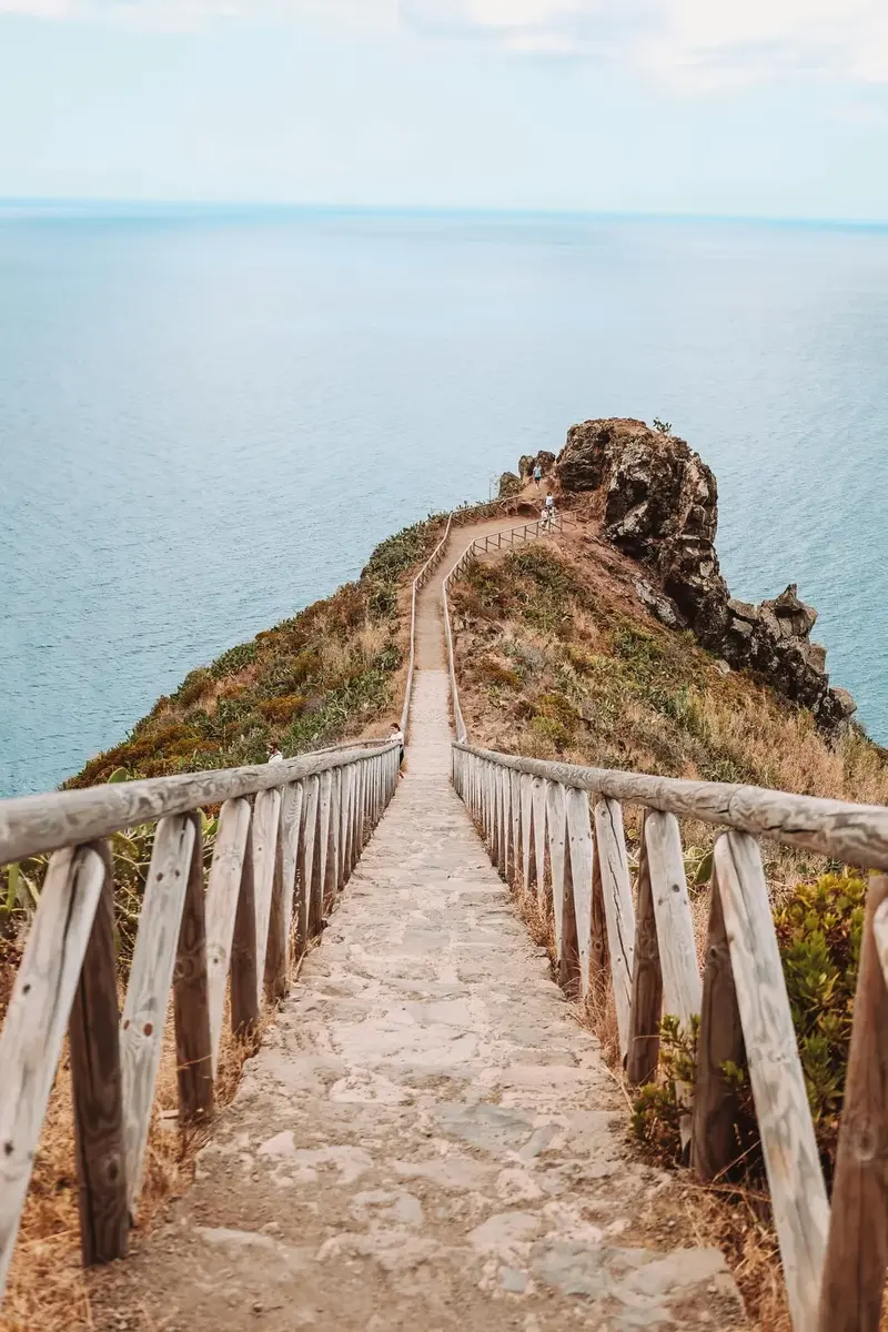 Ce que Madère fait aux voyageurs (et que personne ne dit vraiment) 4 Sentier côtier balisé à Madère avec balustrade en bois descendant vers une pointe rocheuse face à l'Atlantique