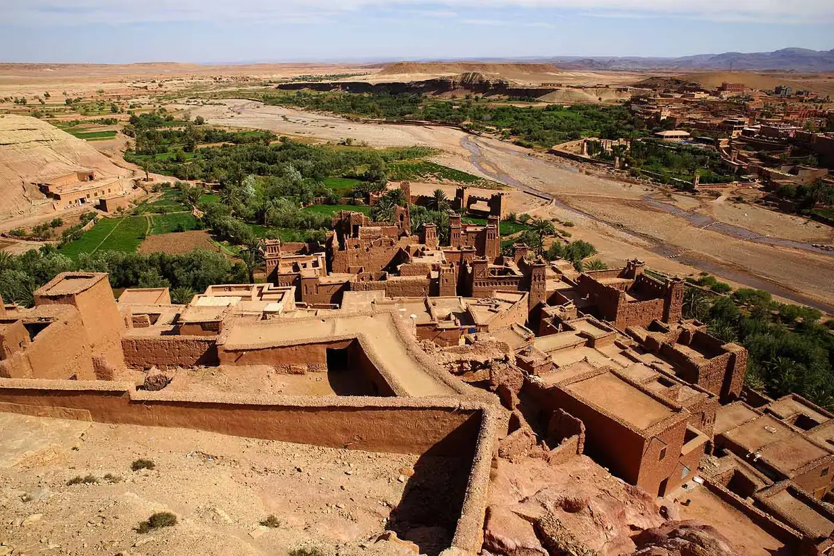 Le ksar d'Aït Benhaddou vu depuis les hauteurs, ses maisons de terre étagées au-dessus de la palmeraie et de la vallée de l'Ounila