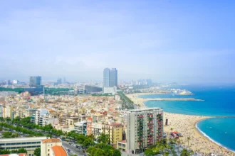 Panorama de Barcelone vu depuis les hauteurs, la ville dense et sa plage filant vers la Méditerranée