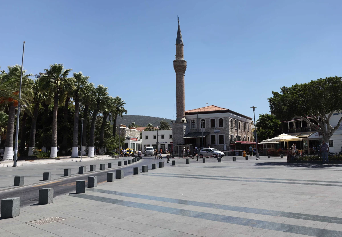 Une place de village de la péninsule de Bodrum, bordée de palmiers avec le minaret de la mosquée