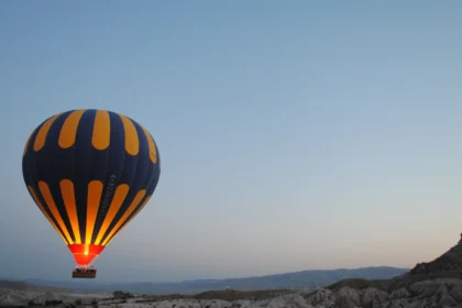 Une montgolfière rayée s'élevant au-dessus des reliefs de Cappadoce au lever du soleil