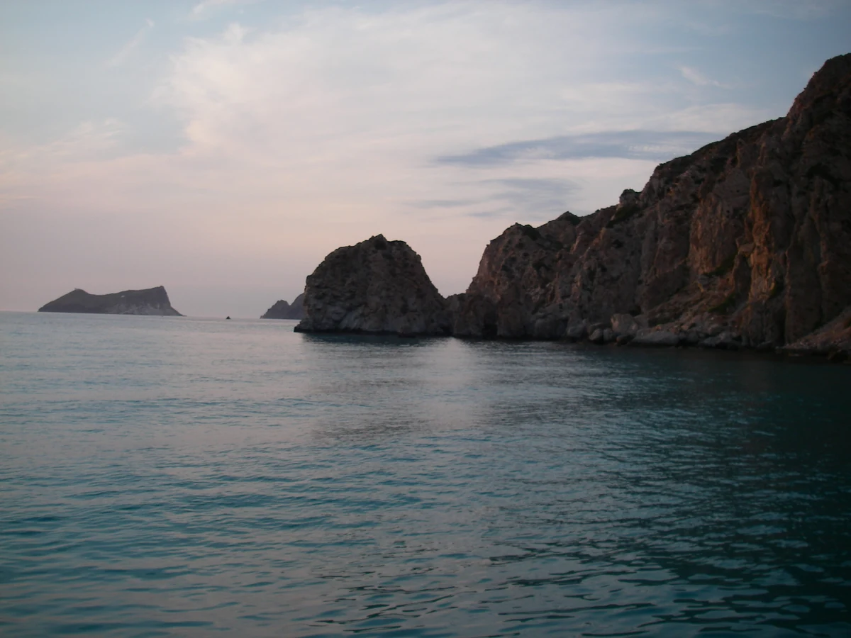 Quand partir en Grèce : la météo mois par mois et le meltemi 2 Côte rocheuse grecque plongeant dans une mer calme au crépuscule