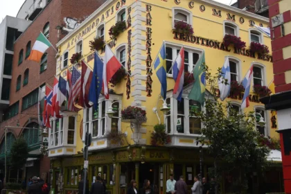 La façade jaune d'un pub du quartier de Temple Bar à Dublin, ses drapeaux et ses clients attablés en terrasse