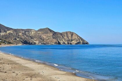 Longue plage de sable déserte se refermant sur un cap aride, sur la côte d'Almería en Espagne