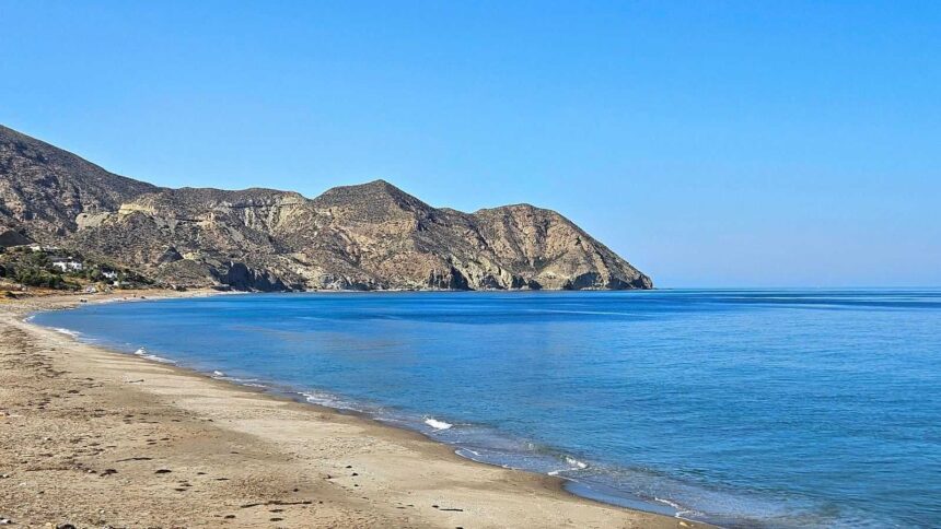 Longue plage de sable déserte se refermant sur un cap aride, sur la côte d'Almería en Espagne