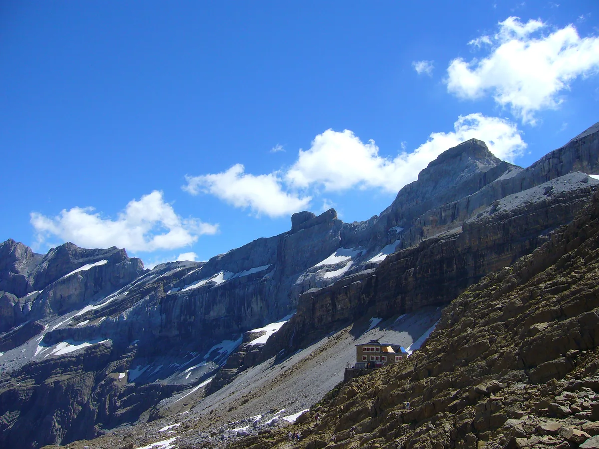 Cirque de Gavarnie : la randonnée jusqu'à la Grande Cascade, itinéraires et conseils 3 Les parois calcaires étagées du cirque de Gavarnie sous un ciel bleu, avec les névés accrochés aux vires
