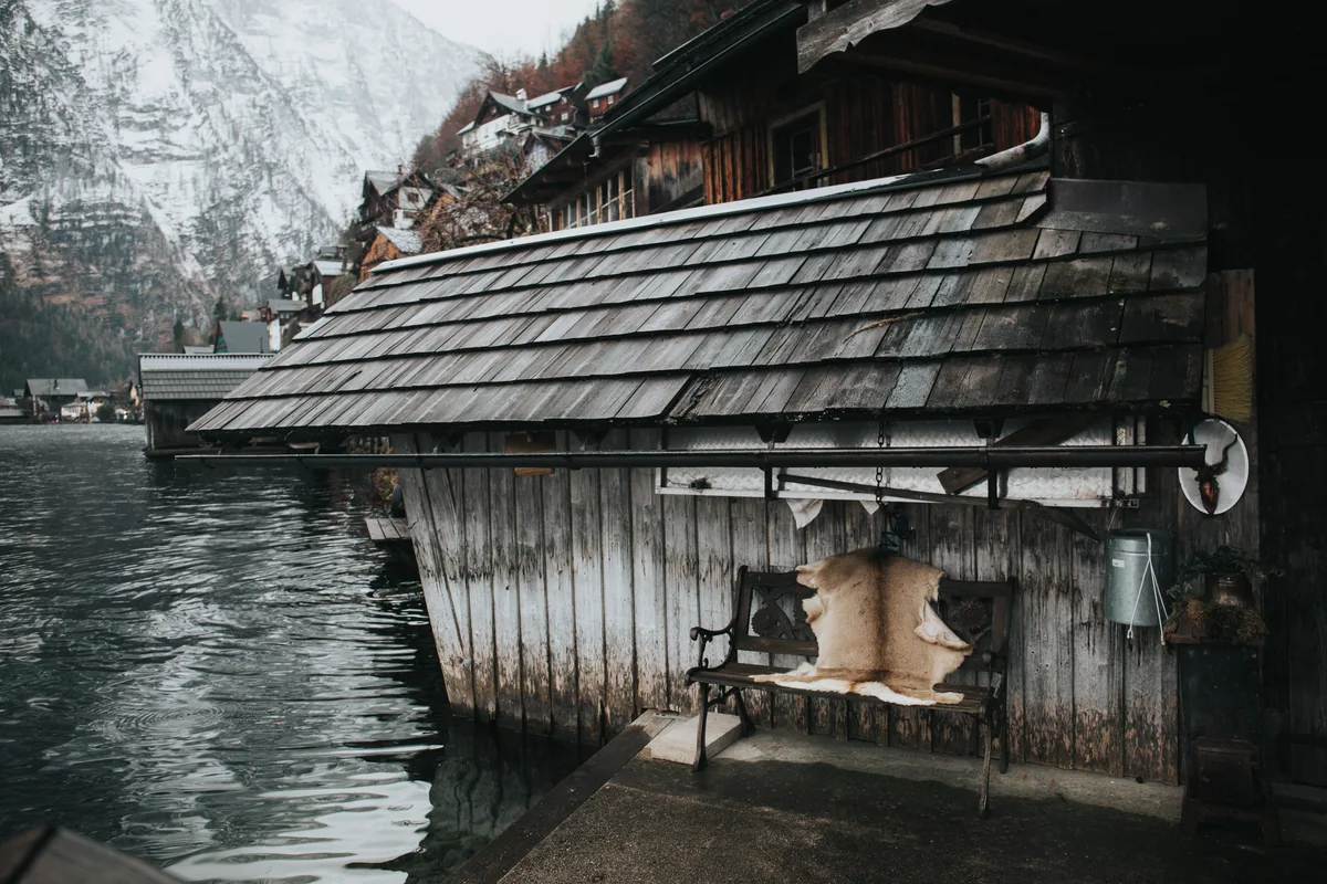 Hallstatt : visiter le village autrichien face à son succès 2 Un hangar à bateaux en bois sombre posé au bord du lac de Hallstatt, ses planches patinées et ses outils suspendus