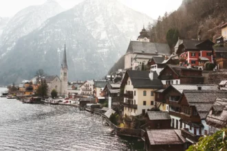 Le village de Hallstatt vu depuis le lac, ses maisons serrées entre l'eau et la montagne autour du clocher de l'église