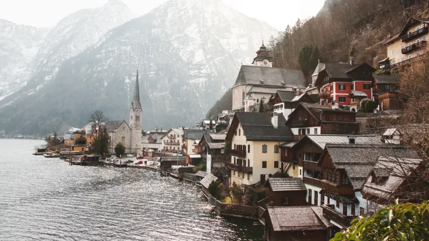 Le village de Hallstatt vu depuis le lac, ses maisons serrées entre l'eau et la montagne autour du clocher de l'église