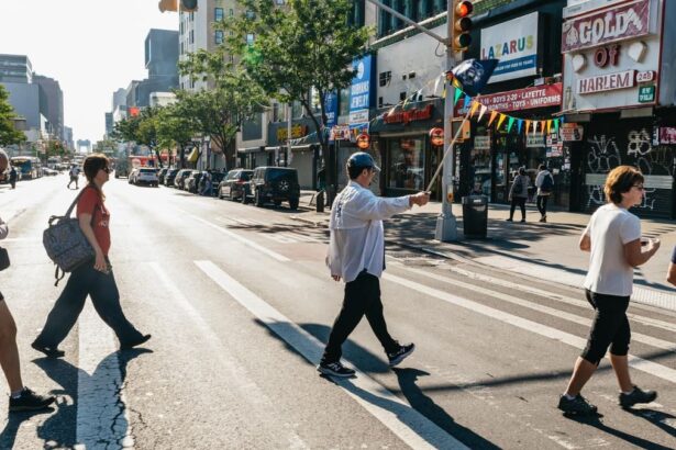 Un guide muni d'un fanion mène son groupe de visiteurs sur un passage piéton d'une avenue de Harlem, devant les boutiques de la 125e Rue