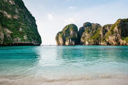 Plage de sable blanc et eau turquoise cernée de falaises calcaires dans les îles Phi Phi