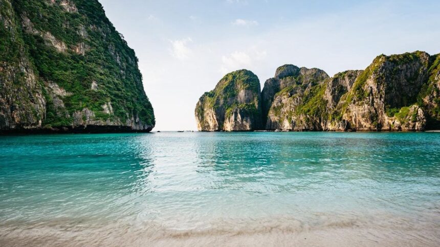 Plage de sable blanc et eau turquoise cernée de falaises calcaires dans les îles Phi Phi