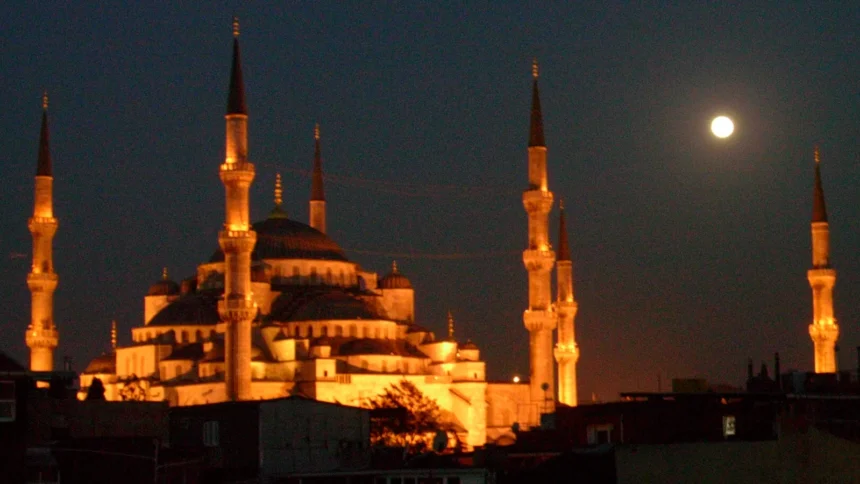 La Mosquée Bleue illuminée à la nuit tombée, ses minarets et ses coupoles se détachant au-dessus des toits d'Istanbul