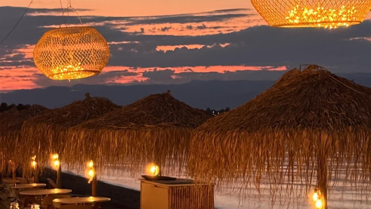 Météores depuis Athènes : les monastères et les grottes cachées des ermites en une journée 7 Terrasse de plage au coucher du soleil à Kamena Vourla, parasols de paille et lanternes allumées face à la mer