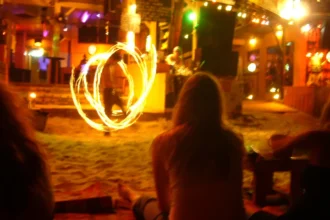 Un spectacle de feu devant un bar de plage de Koh Phangan la nuit, avec les silhouettes des spectateurs