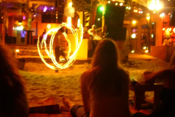 Un spectacle de feu devant un bar de plage de Koh Phangan la nuit, avec les silhouettes des spectateurs