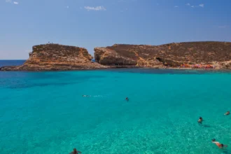 Le Blue Lagoon de Comino à Malte, ses eaux turquoise transparentes entre deux avancées rocheuses et ses baigneurs