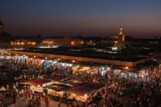 La place Jemaa el-Fna à Marrakech vue d'une terrasse au crépuscule, la fumée des échoppes et le minaret de la Koutoubia au fond