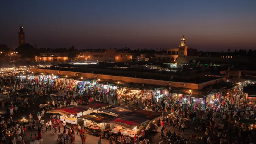 La place Jemaa el-Fna à Marrakech vue d'une terrasse au crépuscule, la fumée des échoppes et le minaret de la Koutoubia au fond