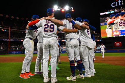 Les joueurs des New York Mets rassemblés en cercle sur le terrain du Citi Field avant un match de baseball en nocturne