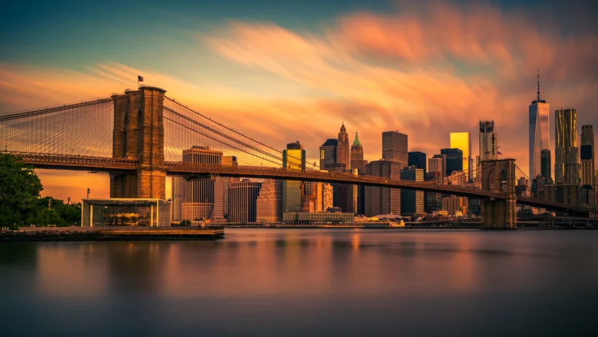 Le pont de Brooklyn et la skyline de Manhattan au coucher du soleil, reflétés dans l'East River