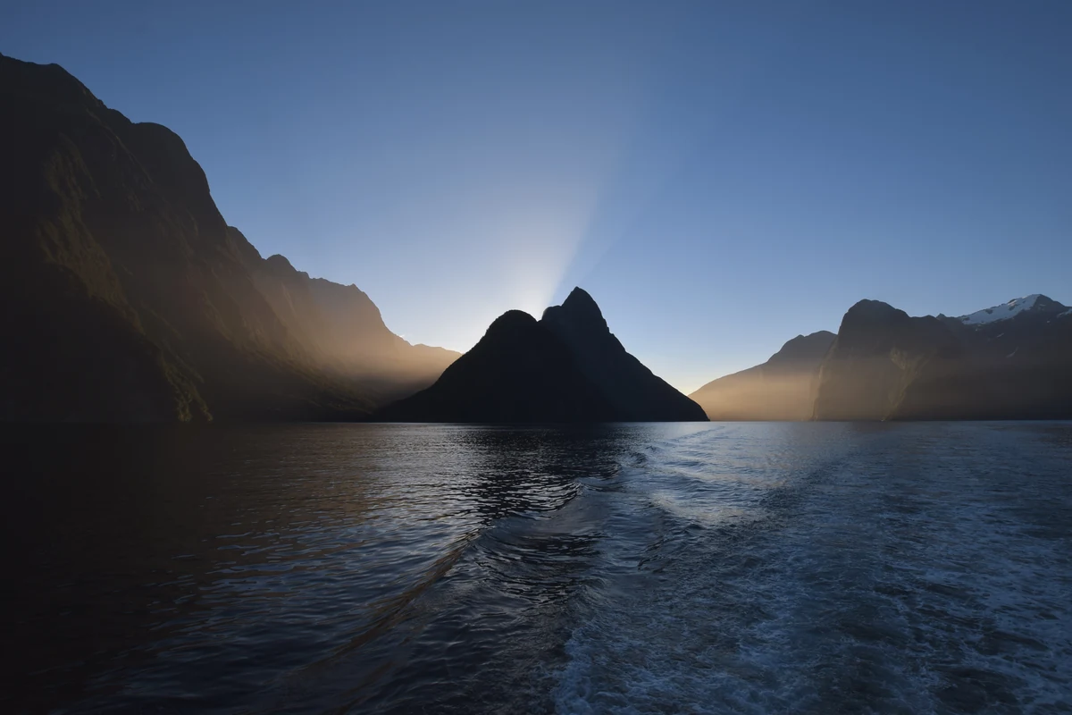 Quand partir en Nouvelle-Zélande : climat, saisons et meilleure période par île 2 Le lever du soleil sur Milford Sound, la silhouette du Mitre Peak se détachant au-dessus de l'eau calme