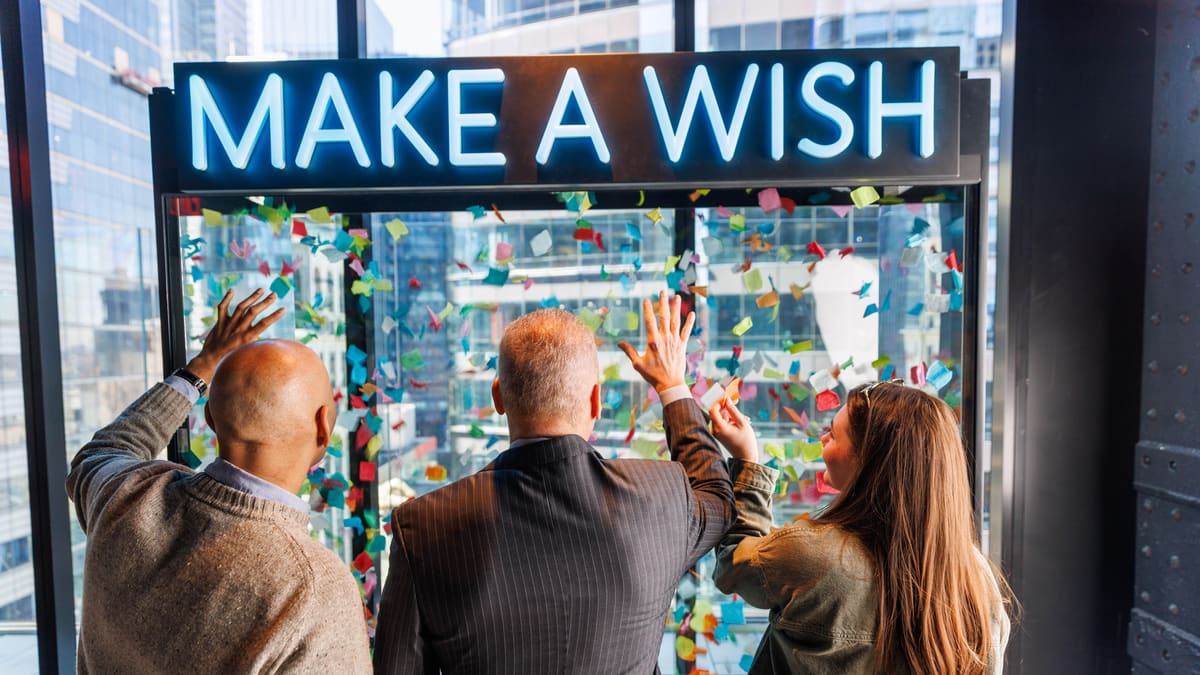 Billets pour le Skywalk One Times Square : prix, horaires et avis du nouvel observatoire 7 Trois visiteurs devant le mur des souhaits de One Times Square, sous l'enseigne lumineuse Make a Wish, la vitrine remplie de confettis colorés