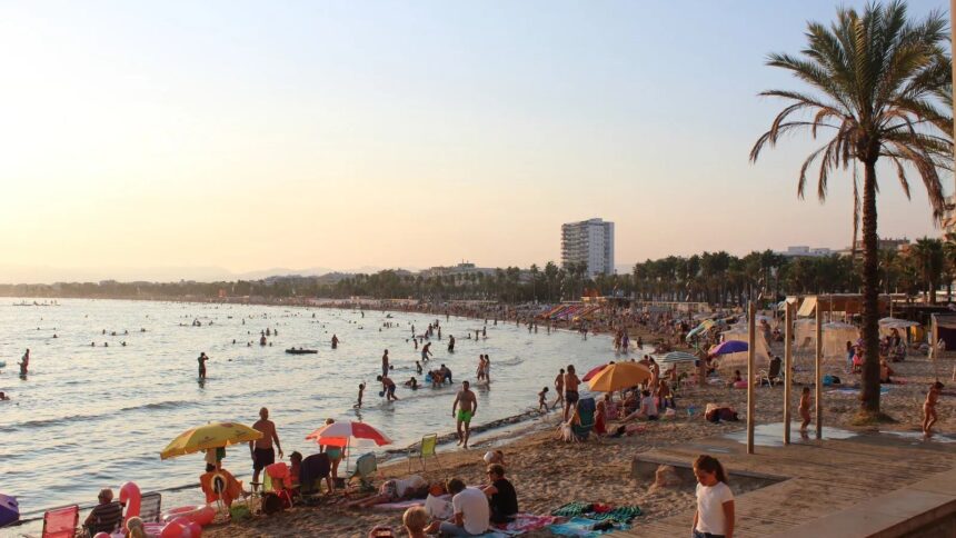 La plage de Salou en fin de journée, avec ses parasols, ses baigneurs et la promenade bordée de palmiers