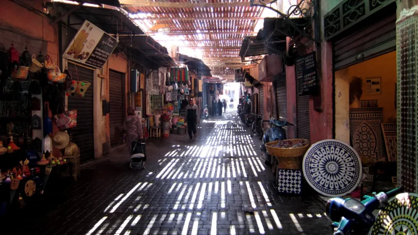 Ruelle du souk de Marrakech traversée par les rais de lumière du toit ajouré