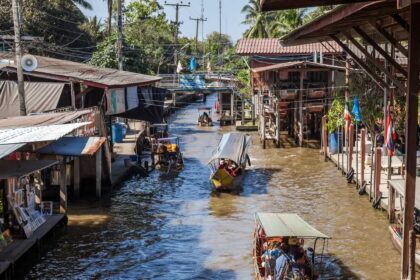 Canal du marché flottant de Damnoen Saduak bordé d'étals en bois et de barques de vendeurs