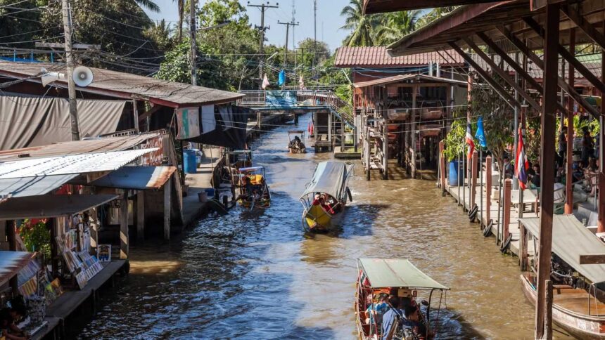Canal du marché flottant de Damnoen Saduak bordé d'étals en bois et de barques de vendeurs