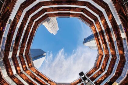 L'intérieur du Vessel à Hudson Yards vu depuis la base, les escaliers de cuivre en nid d'abeille encadrant le ciel et les tours voisines