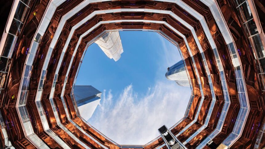 L'intérieur du Vessel à Hudson Yards vu depuis la base, les escaliers de cuivre en nid d'abeille encadrant le ciel et les tours voisines