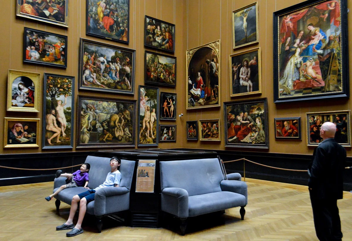 Une salle de peintures anciennes dans un musée viennois, ses toiles accrochées sur mur sombre