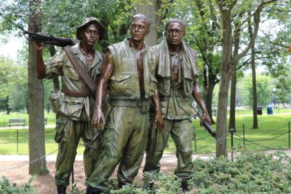 La statue des Trois Soldats du mémorial des vétérans du Vietnam à Washington, trois figures de bronze en tenue de combat au milieu des arbres