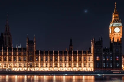 Le palais de Westminster illuminé à la nuit tombée, sa longue façade néogothique et la tour de Big Ben reflétées dans la Tamise