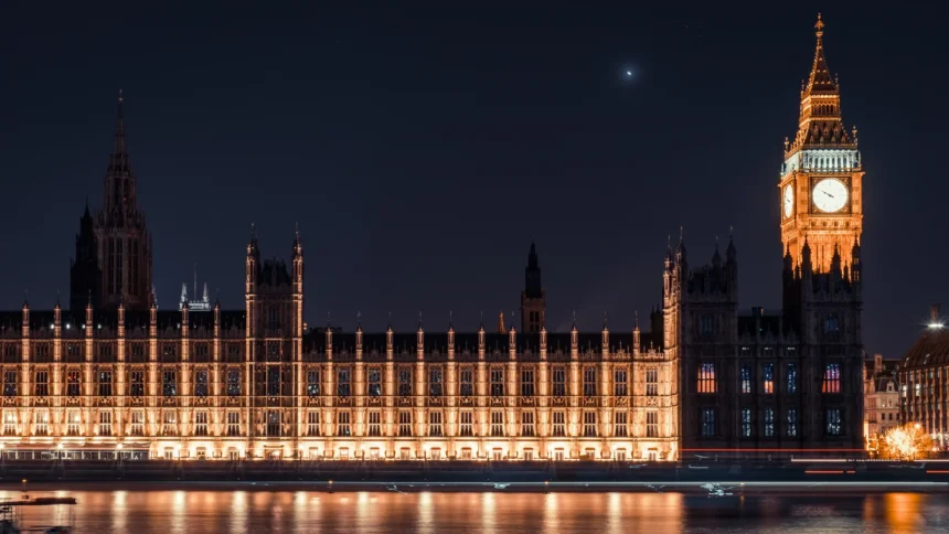 Le palais de Westminster illuminé à la nuit tombée, sa longue façade néogothique et la tour de Big Ben reflétées dans la Tamise