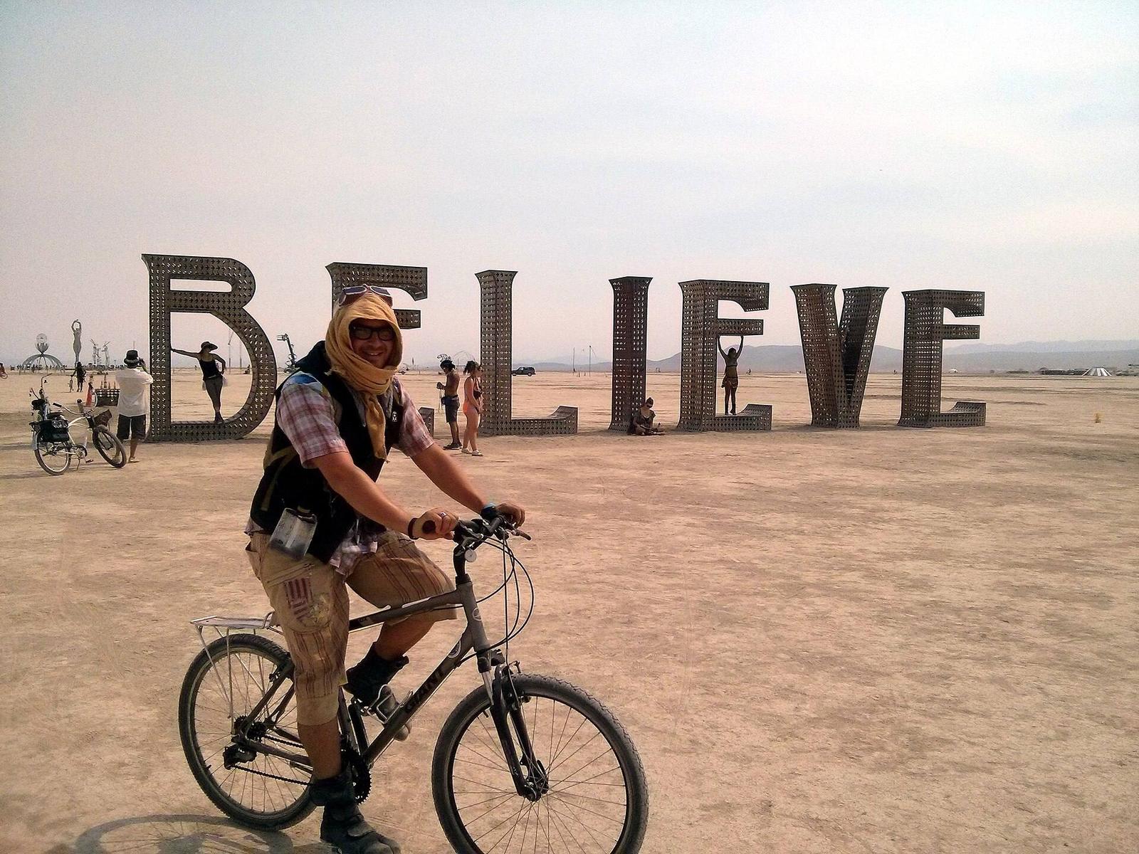 À 40 ans, le Burning Man n'arrive plus à vendre ses billets 4 Un participant au visage protégé de la poussière traverse la playa à vélo devant l'installation BELIEVE