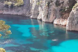 Les eaux turquoise d'une calanque de Cassis entre falaises calcaires et pins, en Provence