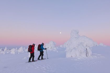 Deux randonneurs en raquettes sur un plateau enneige de Laponie finlandaise, dans la lumiere rose de l aube