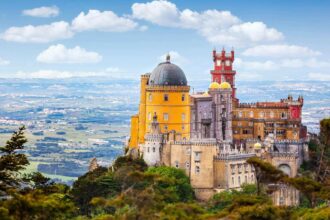 Le palais national de Pena, coupole rouge et façades jaunes, perché sur sa crête boisée au-dessus de la plaine de Sintra