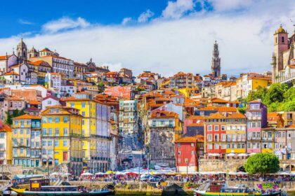 Le quartier de la Ribeira à Porto vu du Douro, façades colorées serrées et bateaux rabelos amarrés au premier plan