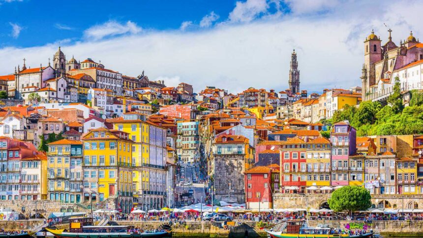 Le quartier de la Ribeira à Porto vu du Douro, façades colorées serrées et bateaux rabelos amarrés au premier plan